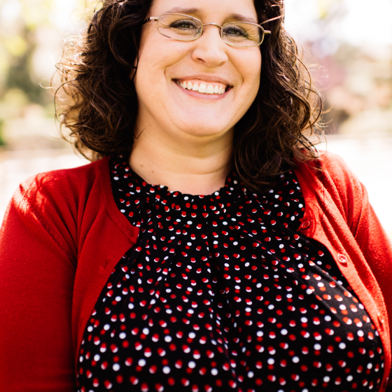 A white woman with brown hair and glasses smiling at the camera.