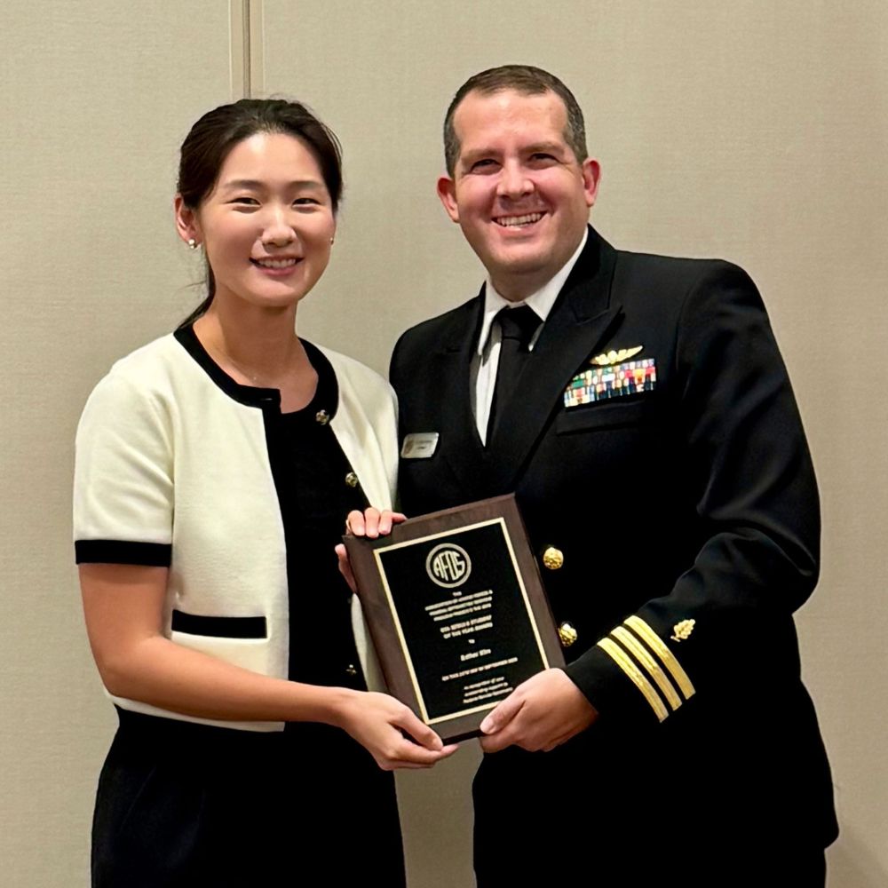 Pacific student Esther Kim, left, is presented the Association of Armed Forces and Federal Optometric Services (AFOS) Colonel Bzdula Student of the Year Award by a man in military uniform.