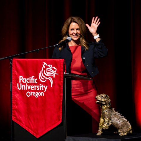 Jenny Coyle waves from a podium next to the original Boxer statue