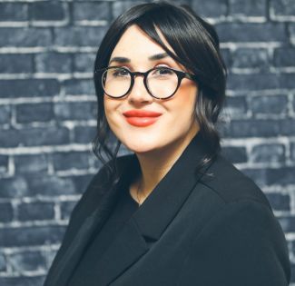 Image of Danielle Walker wearing black shirt, black jacket, black eyeglasses.