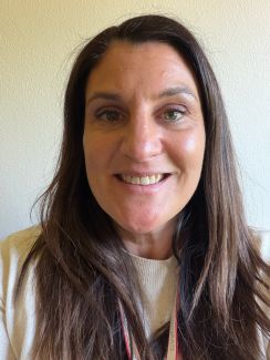 Female with long, straight, brown hair with a plain background.