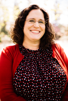 A white woman with brown hair and glasses smiling at the camera.