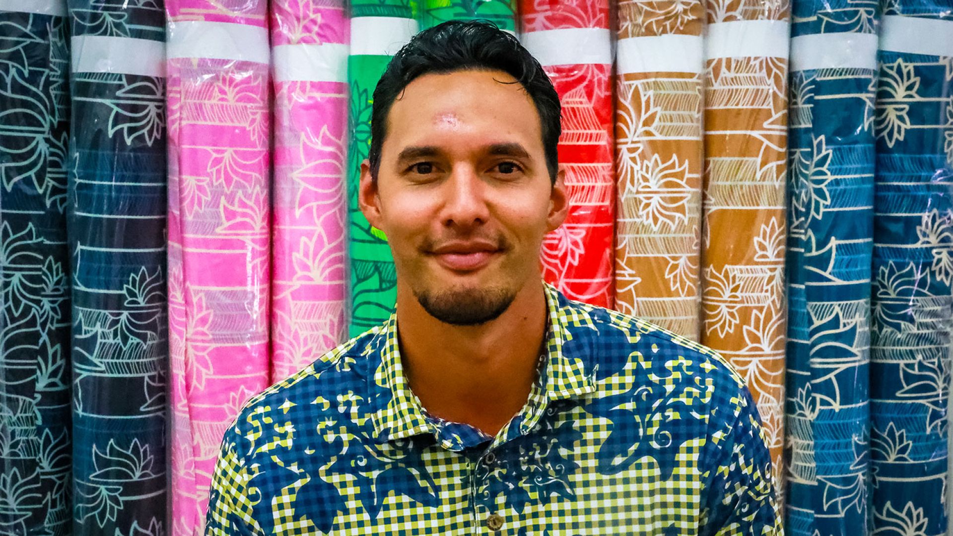 Lokahi Lunn '11 In front of rolls of Hawaiian print fabric