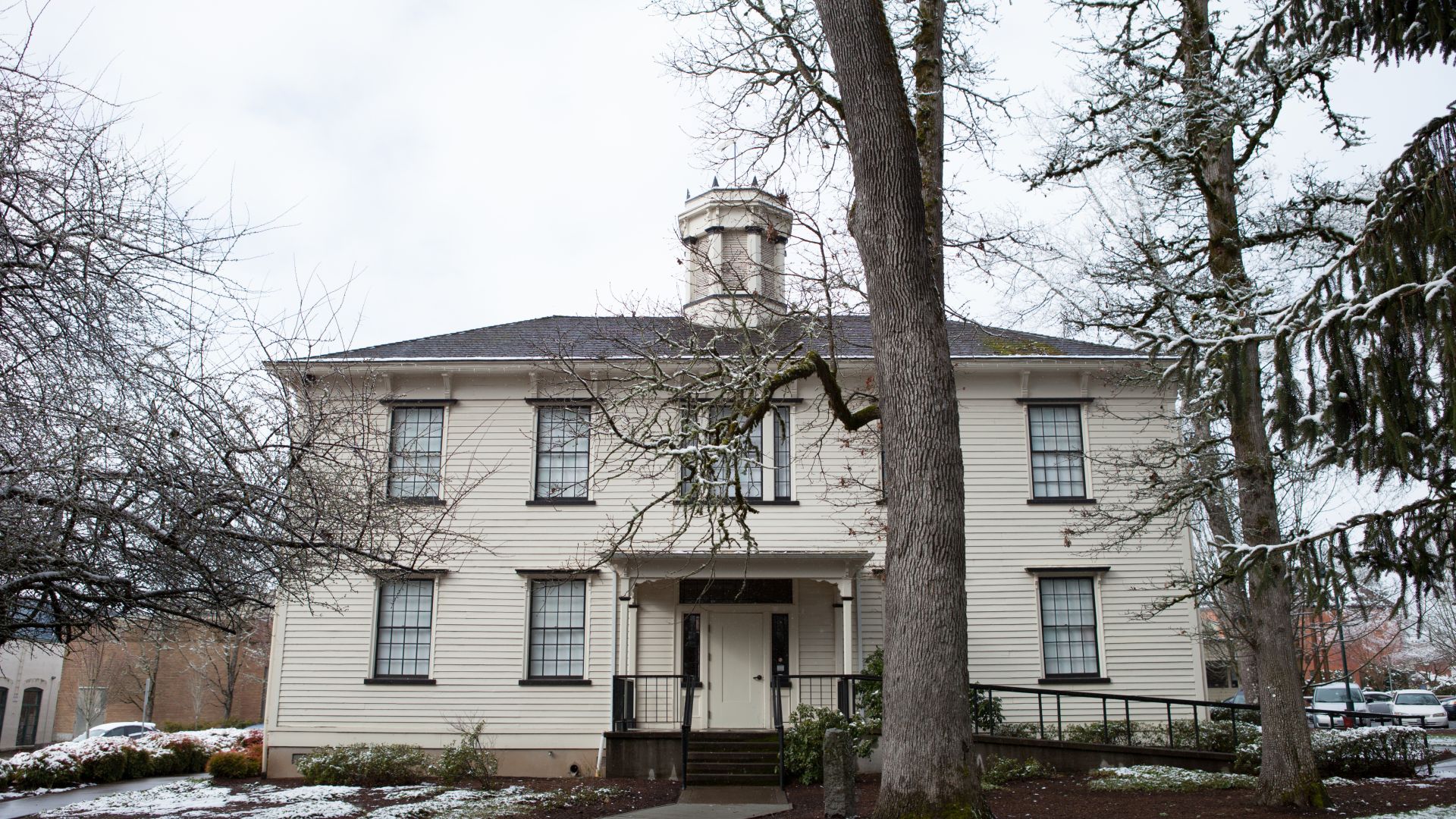 Photo of Old College Hall taken in the winter, there is snow on the ground and the trees in front have lost their leaves.
