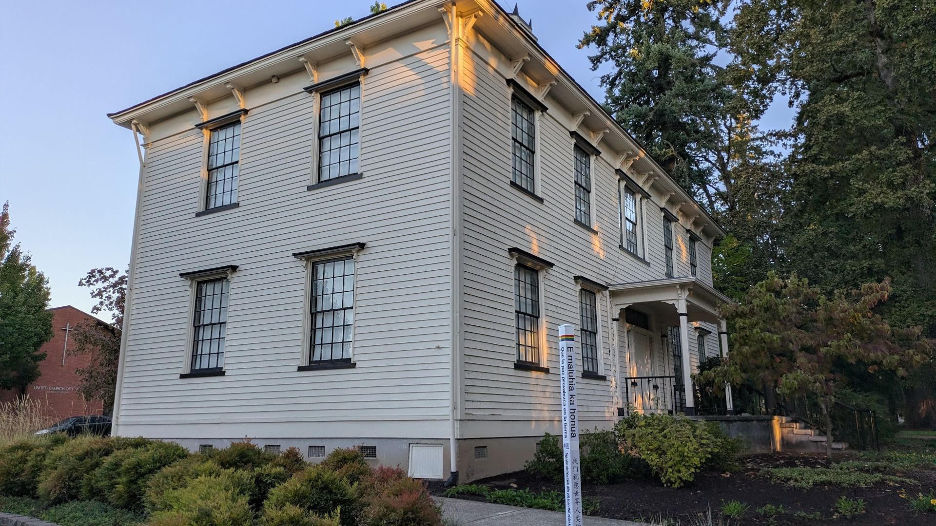 Photo of Old College Hall with the newly installed Peace Pole sponsored by the Rotary Club of Forest Grove in the foreground.