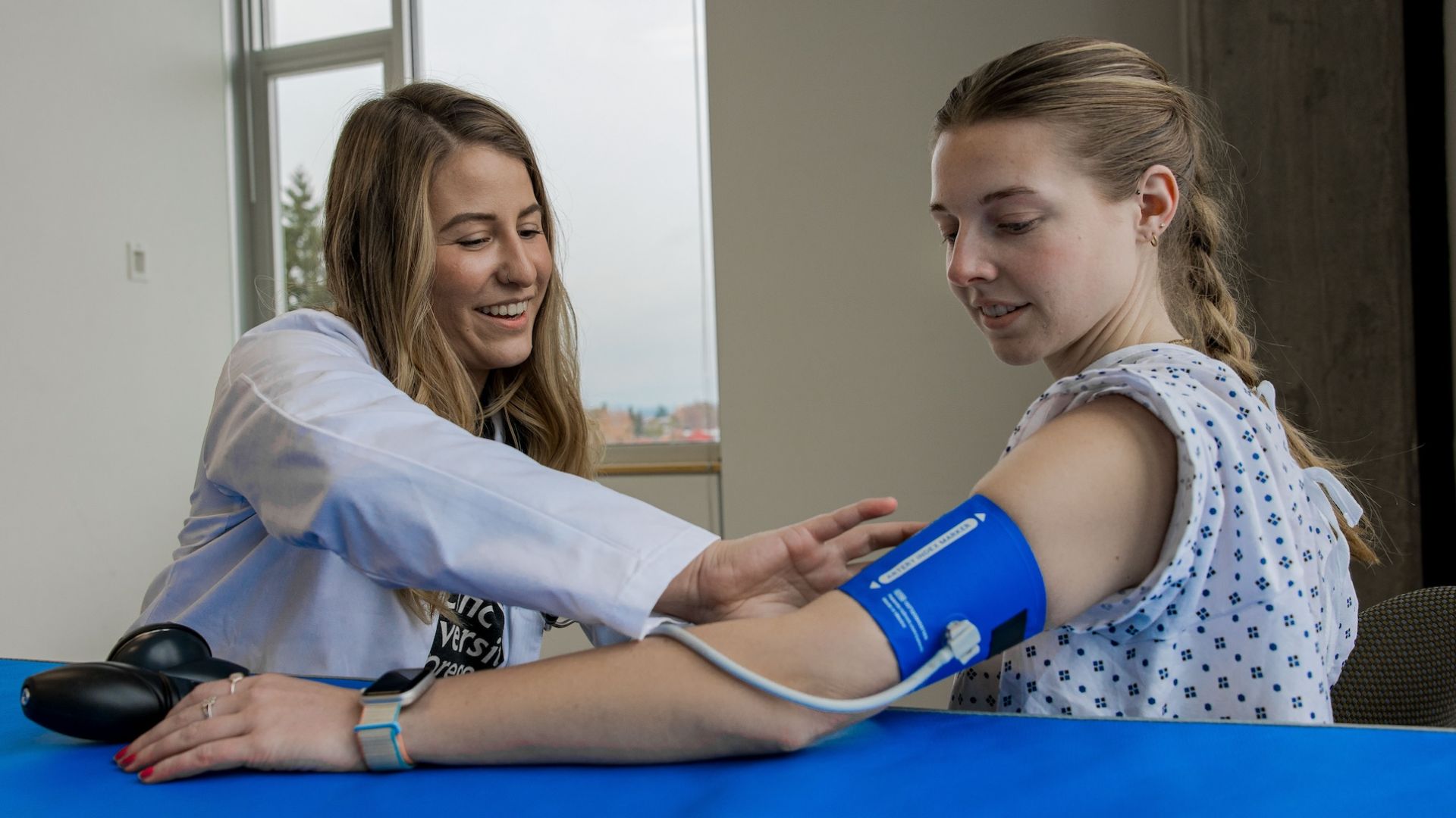 Pacific student checking blood pressure on a female patient