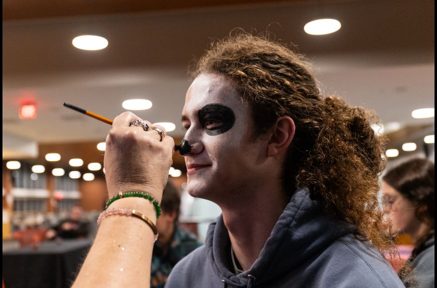 A student has their face painted for Día de los Muertos