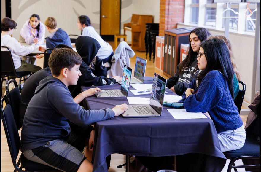 College students host a game session with middle school students playing on computers
